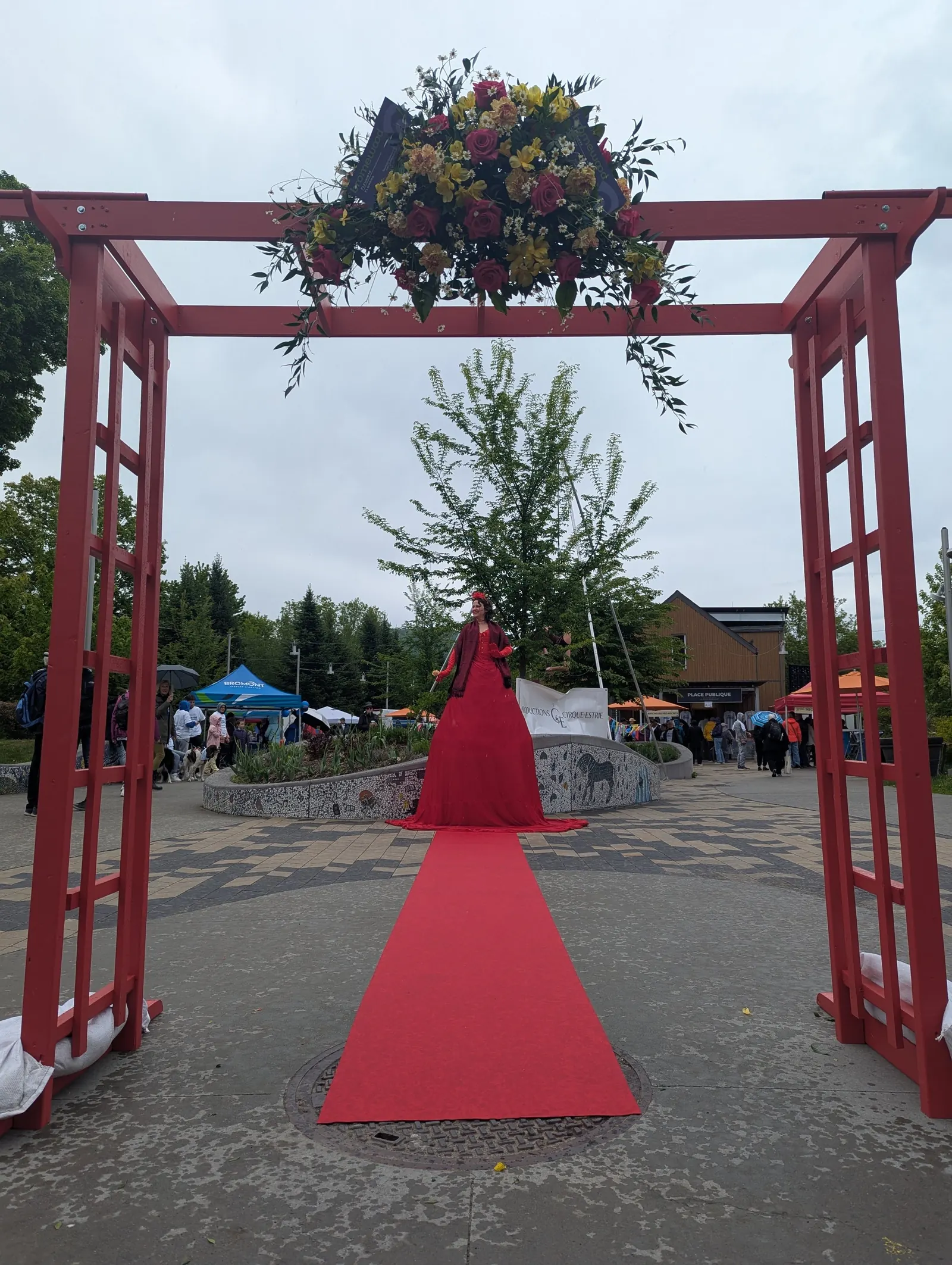 Portique rouge fleuri et tapis rouge menant à un personnage en robe rouge