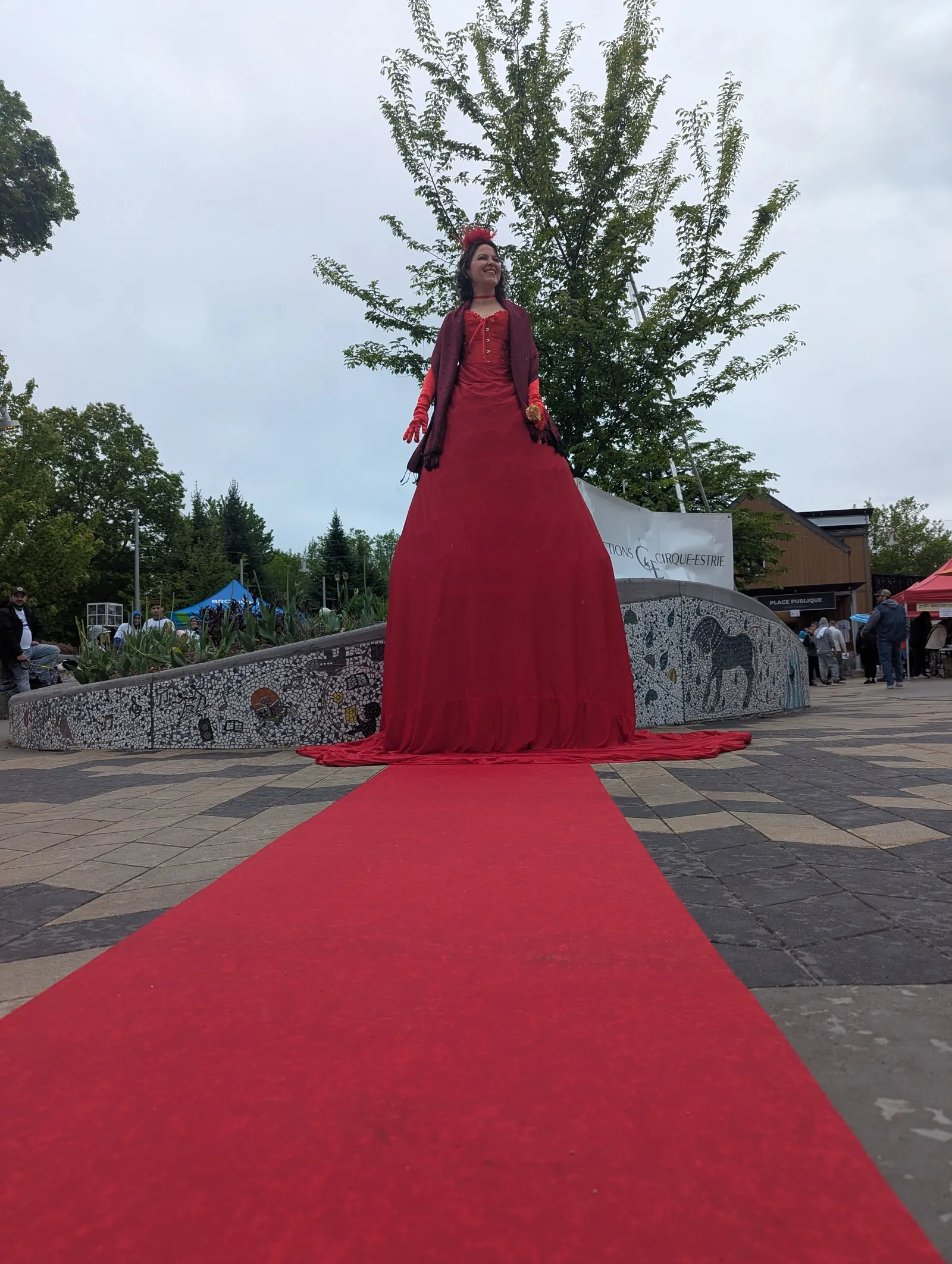 Personnage en immense robe rouge au bout d'un tapis rouge