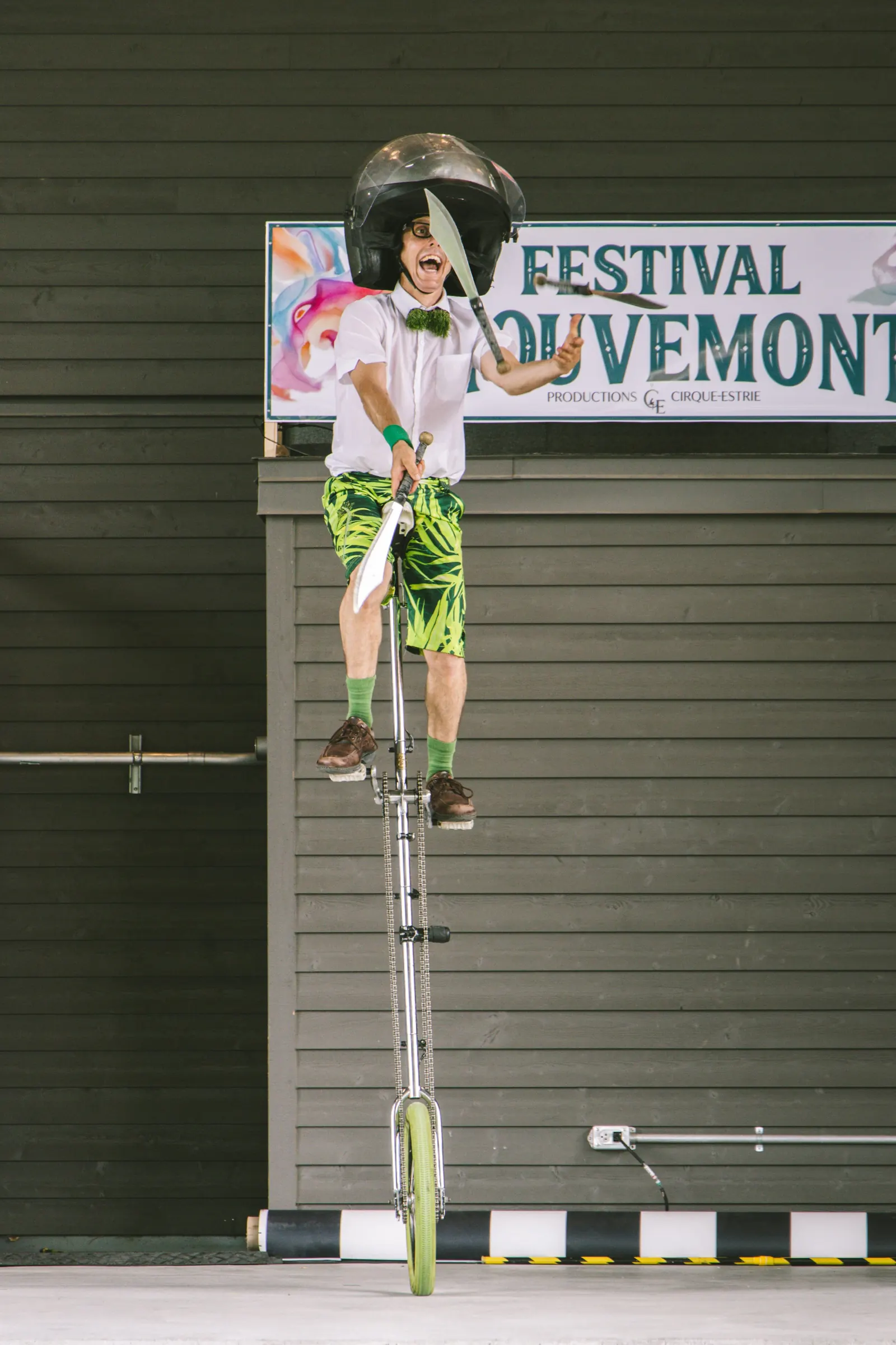 Artiste sur un monocycle géant devant la bannière du Festival MouveMont