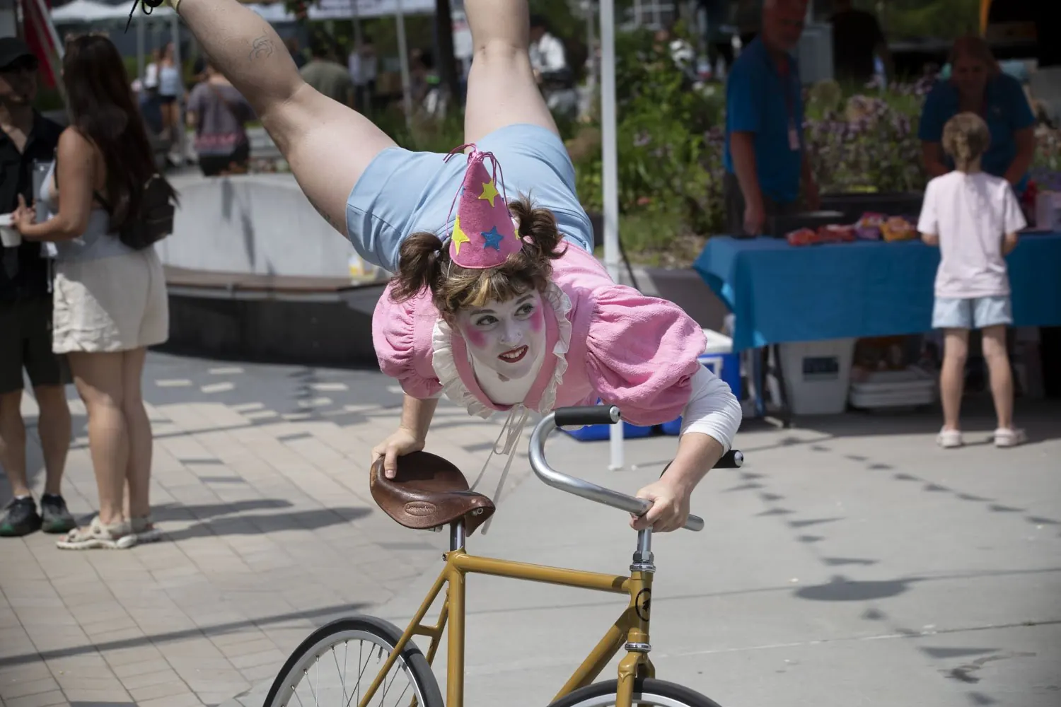 Artiste clown en équilibre acrobatique sur un vélo devant le public